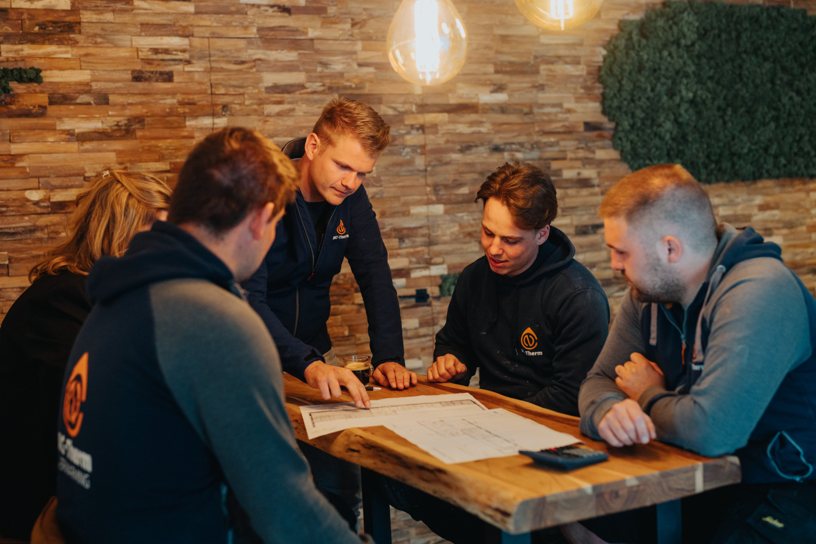 Vijf medewerkers van NC Therm overleggen in een gezellige vergaderruimte
