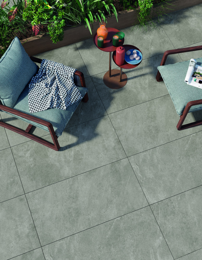 Stijlvol terras met grote, grijze keramische buitentegels in natuursteenlook, gecombineerd met loungemeubilair en plantenbakken voor een strak geheel. Keramische buitentegels in moderne tuinsetting