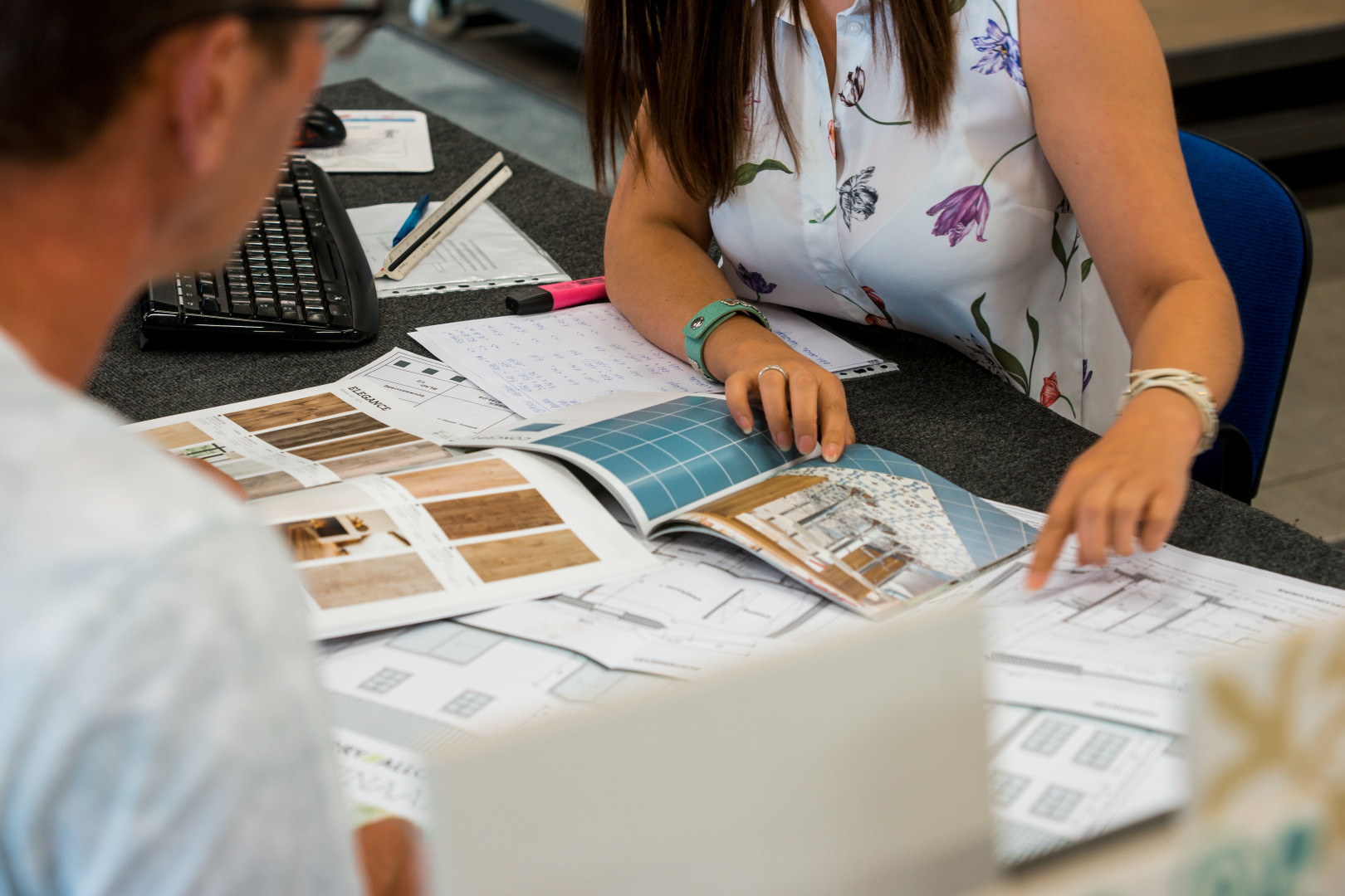 Persoonlijk interieuradvies bij Tegelhandel Kwanten Twee personen bespreken vloer- en wandtegels aan een tafel met catalogi en bouwplannen bij Tegelhandel Kwanten in Pelt.