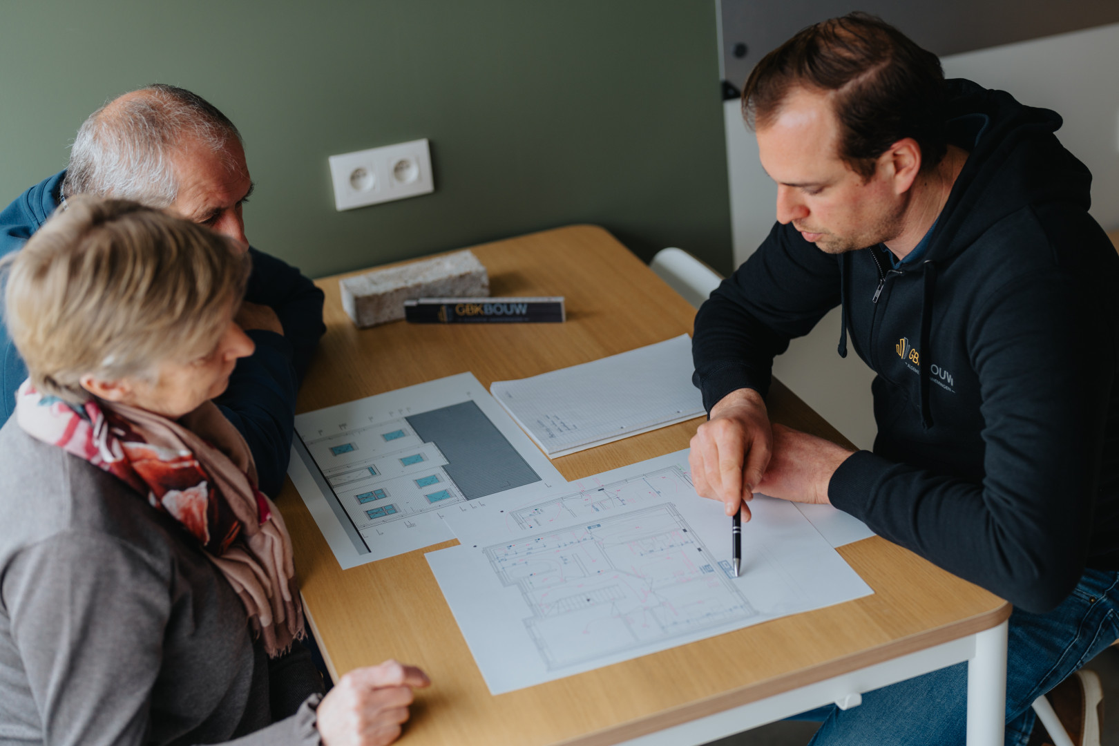 Sleutel-op-de-deur bouwen met GBK Bouw: persoonlijk bouwadvies op maat Bouwadviseur van GBK Bouw bespreekt bouwplannen met klanten tijdens een sleutel-op-de-deur traject, met bouwtekeningen op tafel.