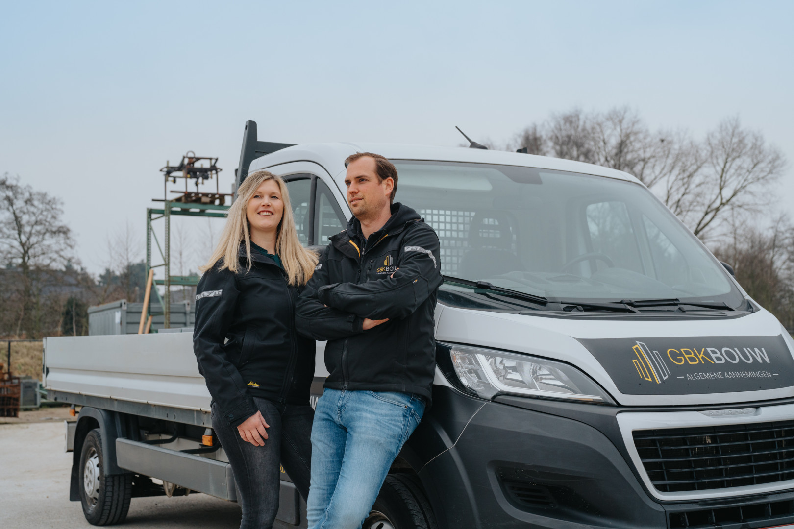 Zaakvoerders van GBK Bouw aan het werk op de werf Zaakvoerders van GBK Bouw poseren voor hun bedrijfsvoertuig op een werflocatie, met werfkledij en professioneel materiaal op de achtergrond.