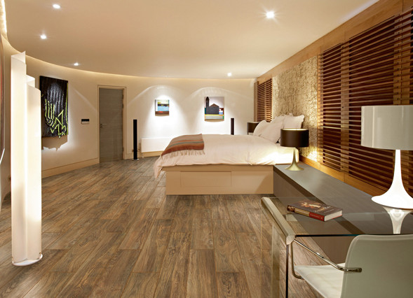 Parketvloer met warme houtlook in moderne slaapkamer Stijlvolle slaapkamer met warme parketvloer in houtlook, moderne verlichting, kunst aan de muur en een strakke inrichting met bureau en groot bed.
