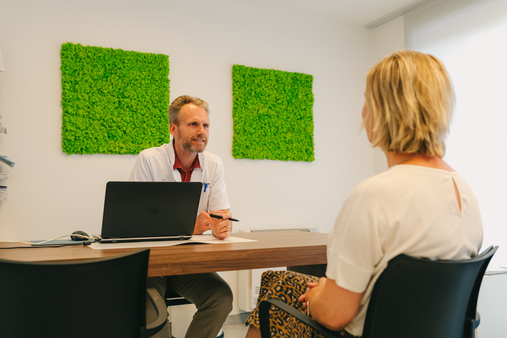 Consultatiegesprek bij The Face Clinic Een arts van The Face Clinic voert een persoonlijk consultatiegesprek met een patiënte in een rustige en professionele setting.