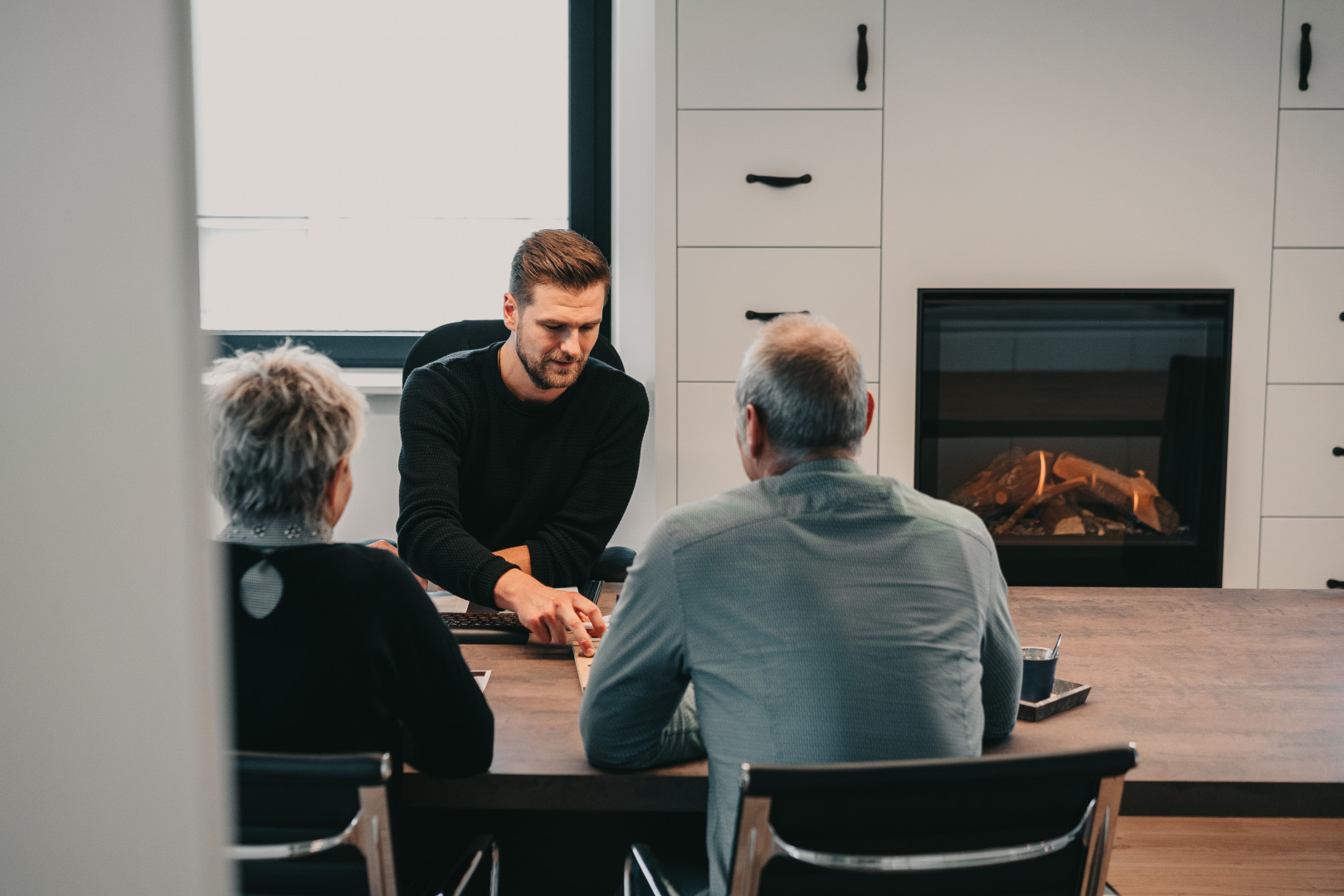 Persoonlijk haardadvies in de showroom van Schouwen André Adviseur van Schouwen André geeft persoonlijk haardadvies aan klanten in de showroom met gashaard en maatkasten op de achtergrond