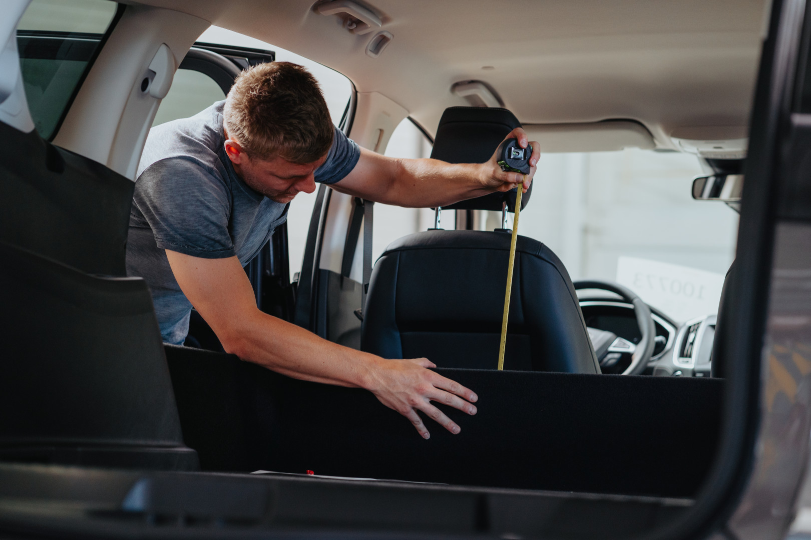AWB-medewerker voert nauwkeurige metingen uit in het interieur van een wagen tijdens de voorbereiding van de ombouw naar lichte vracht.