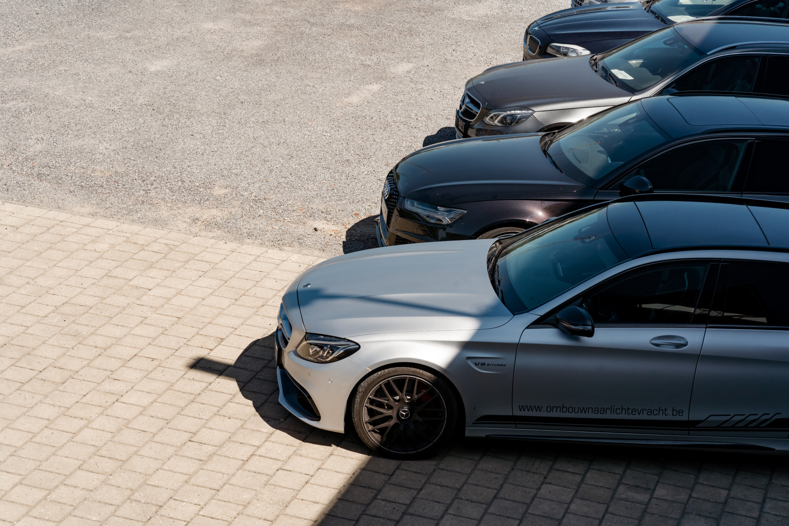 Lichte vrachtwagens en stockwagens op de parking van AWB in Balen Geparkeerde premiumwagens, waaronder Mercedes en Audi, klaar voor ombouw tot lichte vracht bij AWB in Balen