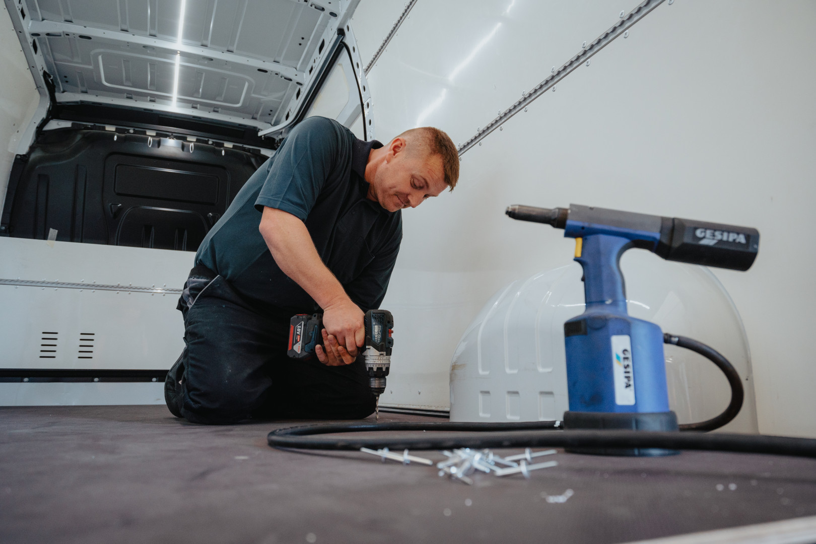 AWB-medewerker voert technische aanpassingen uit aan een voertuig tijdens de ombouw naar lichte vracht, met professioneel gereedschap in de werkplaats.