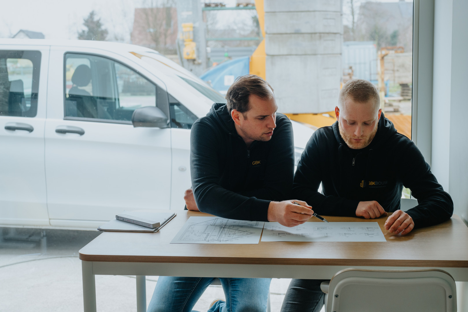 Overleg bouwproject GBK Bouw Twee projectleiders van GBK Bouw bespreken bouwplannen tijdens een werfoverleg.
