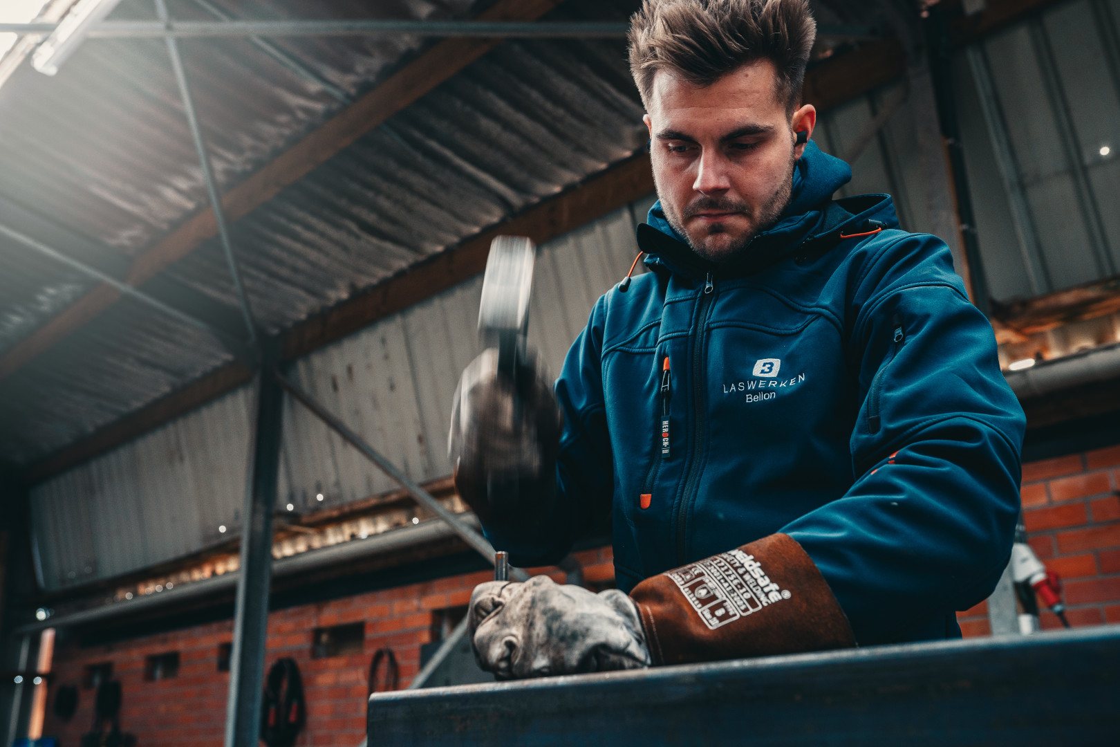 Lasser met hamer aan het werk in atelier
